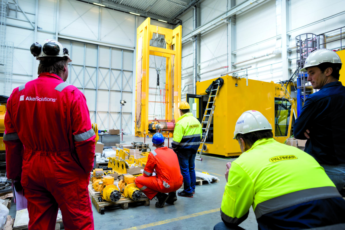 Five engineers in work gear conduncting offshore crane tests in a hall